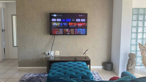 Ein Wohnzimmer mit einem an der Wand montierten Flachbildfernseher, der eine Streaming-Dienstanwendung zeigt.