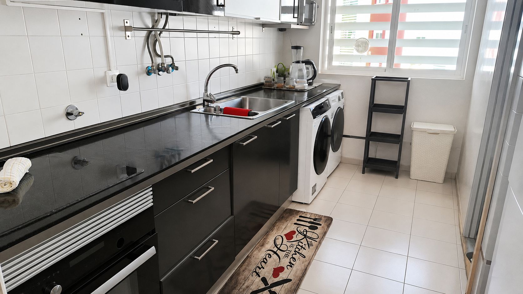 Una cocina moderna con lavadora, un lavamanos y una ventana con persianas.