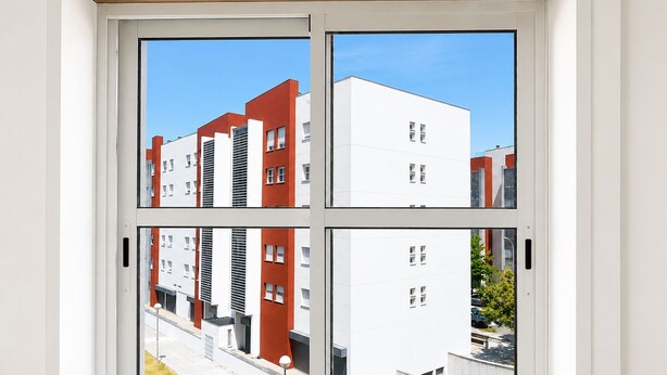 A window with a view of a modern building complex, featuring multiple buildings with varying architectural styles. - Room-singh Leite Holiday Home (Lisbon)