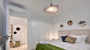 A bedroom with a bed, a green throw, a SuperHost sign, a unique light fixture, and a door leading to another room. - Le Bohémien Signature Apartment in La Marsa (La Marsa)