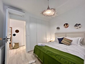 A bedroom with a bed, a green throw, a SuperHost sign, a unique light fixture, and a door leading to another room. - Le Bohémien Signature Apartment in La Marsa (La Marsa)