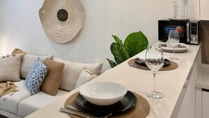 A modern kitchen with a central island, pendant lighting, an air conditioning unit, and a decorative wall hanging. - Le Bohémien Signature Apartment in La Marsa (La Marsa)