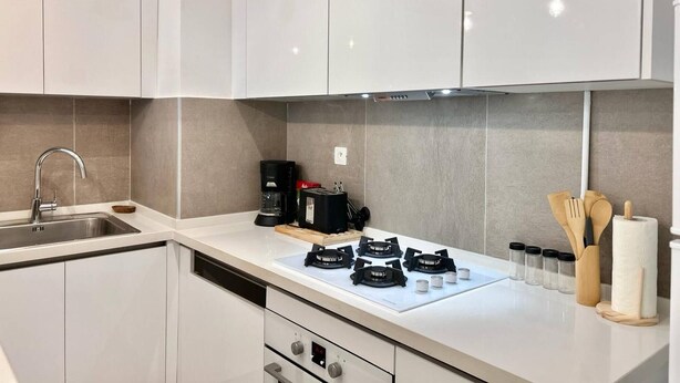 A modern kitchen with white cabinets, a stainless steel sink, a coffee maker, and a gas stove. - Le Bohémien Signature Apartment in La Marsa (La Marsa)