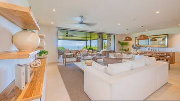 Un salón moderno con un sofá blanco, estanterías de madera y vistas al mar.