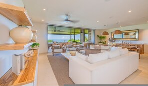 Ein modernes Wohnzimmer mit einem weißen Sofa, Holzböden und Blick auf das Meer.