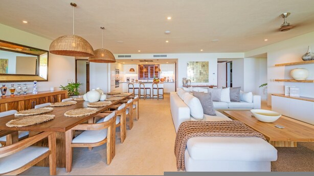 A spacious living area with a dining table, sofas, and a kitchen in the background. - Condo Ensue o 3BD - Tau Punta Mita (Punta de Mita)