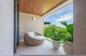 Ein Balkon mit einem Korbstuhl und einem Blumentopf.