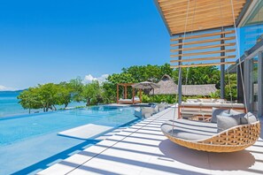 A modern infinity pool with a clear view of the sea, outdoor seating, and a thatched-roof structure. - Casa Brisa 7BD - Kupuri Punta Mita (Punta de Mita)