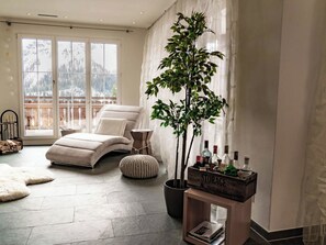 A spacious living room with a large window, a comfortable sofa, a potted plant, and a wooden storage unit. - Amore Appartement/Fewo, Dusche und Bad, WC, 6-Bettwohnung by Interhome (Arosa)