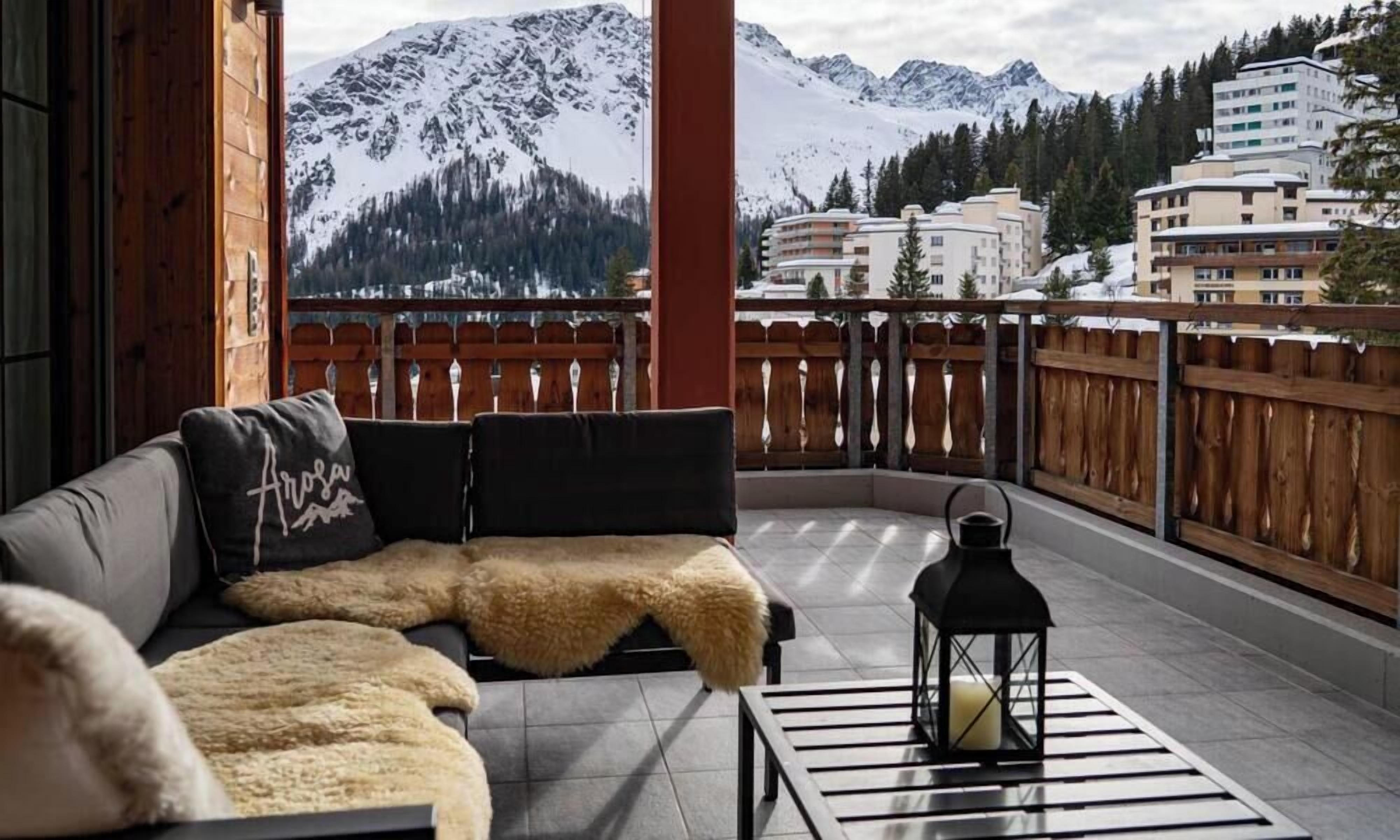 Ein Balkon mit einer Couch, einem Fellüberwurf und einer Laterne.