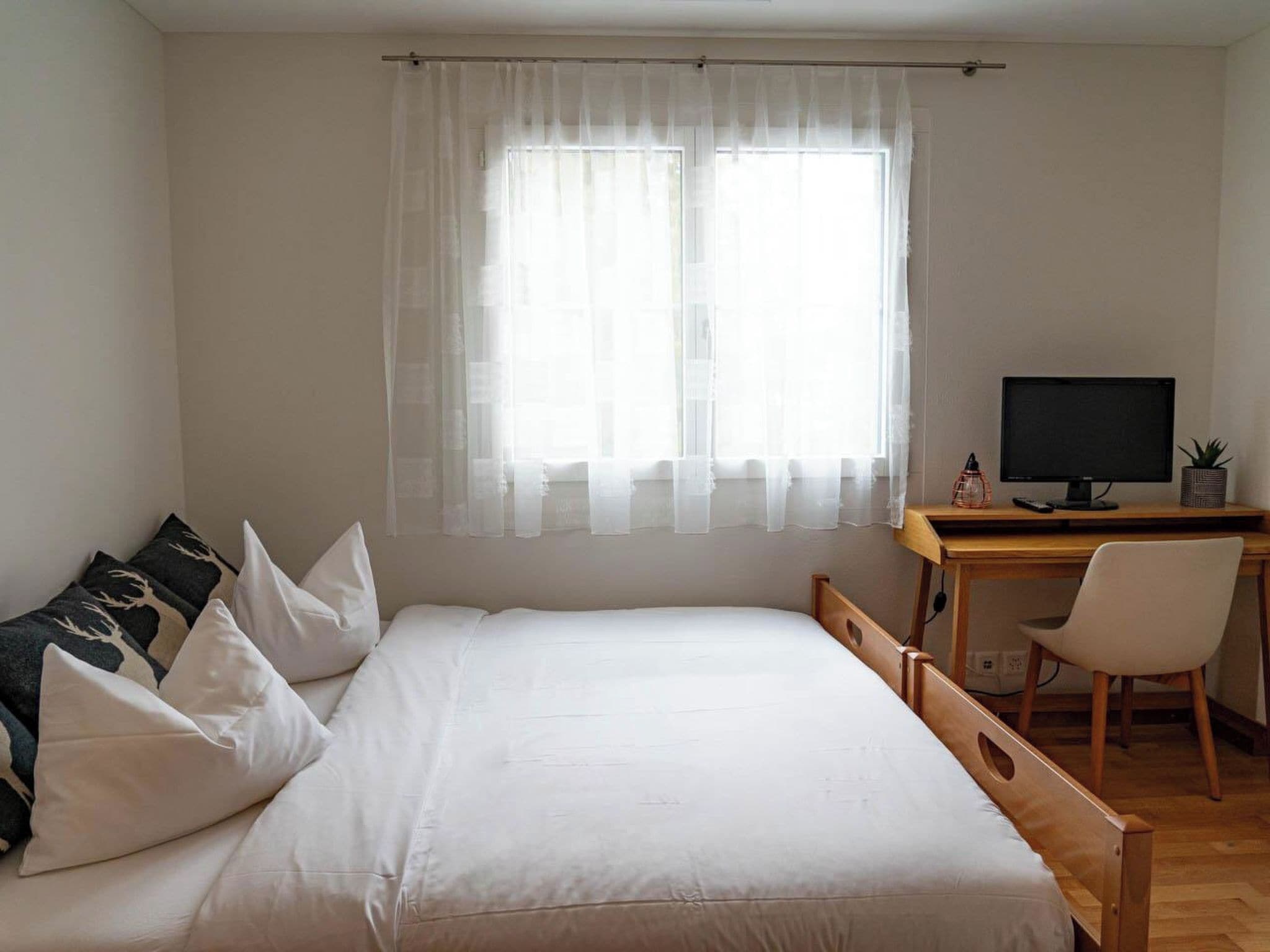 Une chambre à coucher avec un lit, un bureau avec un ordinateur et une chaise.