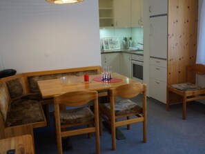 Ein Essbereich mit einem Holztisch und Stühlen, einer roten Kerze und einer Küche im Hintergrund.