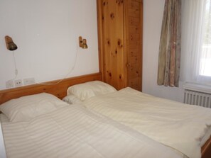Ein Doppelbett mit Holzüberbau, eine Nachttischlampe und ein Fenster mit Vorhängen.