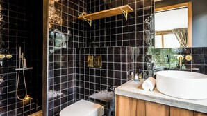 A bathroom with black tiled walls, a white sink, and a shower area. - Chalet Noyer - Luxury 4 bedroom chalet only a short walk from Chamonix centre (Chamonix)