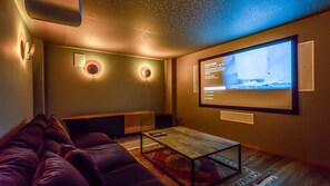 Ein gemütliches Wohnzimmer mit einem großen Flachbildfernseher an der Wand, einer bequemen Couch und einem Couchtisch.