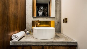 Ein Badezimmer mit einem runden weißen Waschbecken, einer Holztür und einem Spiegel über dem Waschbecken.
