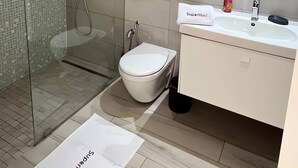 Un baño moderno con cabina de ducha de vidrio, inodoro blanco y lavamanos con espejo.