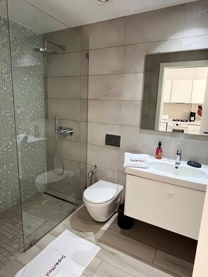 A modern bathroom with a glass shower enclosure, a white toilet, and a sink with a mirror above it. - B15 Cozy Apartment in La Marsa (La Marsa)