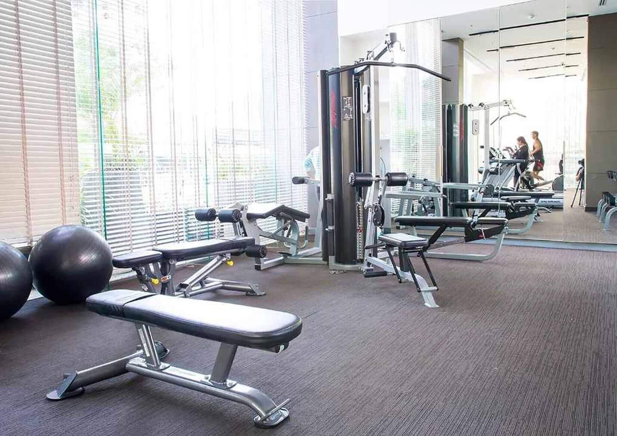 A gym with exercise equipment, a bench, and a mirror.