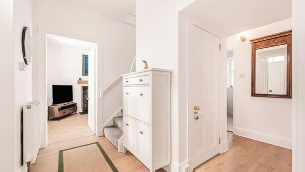 A hallway with a white wardrobe, a door with a mirror, and a staircase leading to another room. - Cromar Cottage in Aberdeenshire (Ballater)