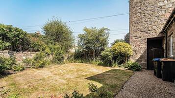 A stone building with a grassy yard, a gravel path, and a wooden fence.