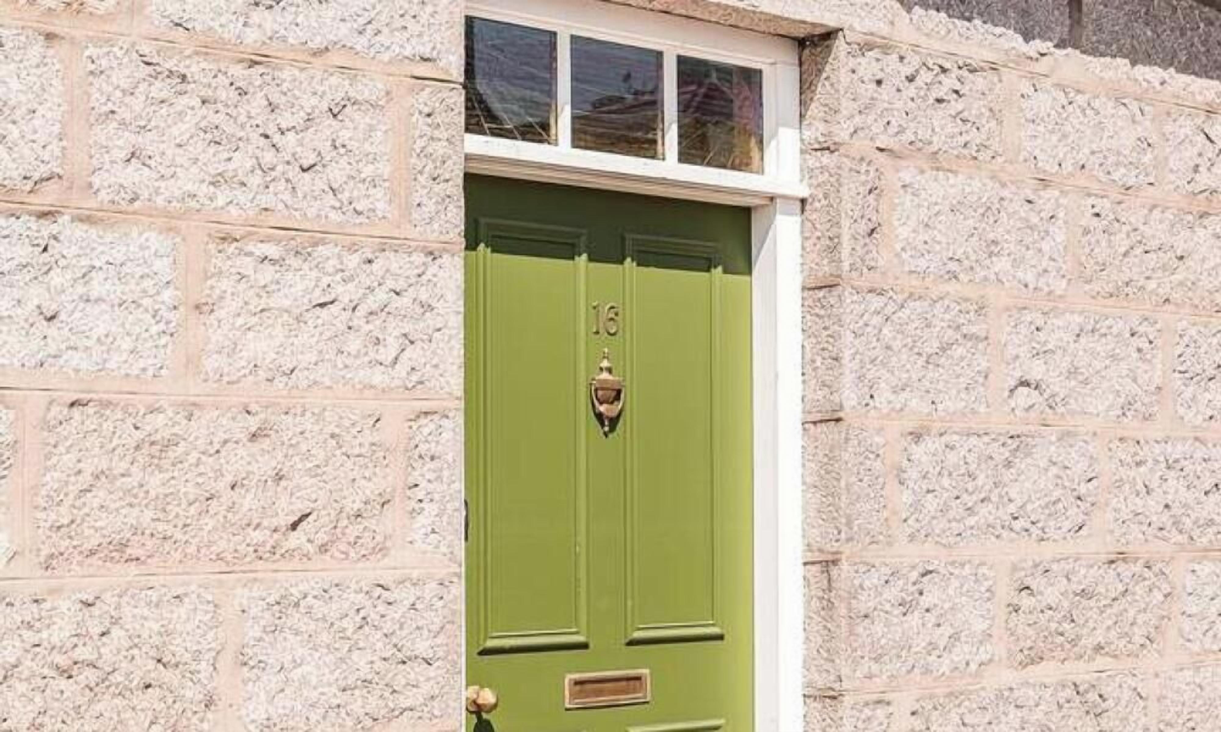 A green door with the number 16, set in a stone wall.