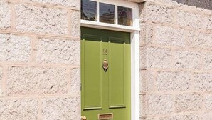 A green door with the number 16, set in a stone wall. - Cromar Cottage in Aberdeenshire (Ballater)