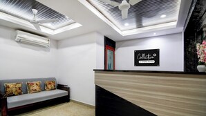 Un espace d’accueil comprenant un canapé, un comptoir de réception et un ventilateur de plafond.
