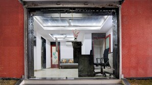 Un espace d’accueil doté d’une porte vitrée, d’un comptoir de réception, d’une chaise et d’un escalier menant à un niveau supérieur.