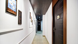 Un couloir aux murs blancs, doté d’un sol en marbre et d’une porte en bois avec une plaque portant un numéro.