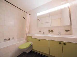 A bathroom with a toilet, a shower, and a sink with a mirror above it. - I dr Rehwiesa A16 Appartement/Fewo, Bad, WC, 4-Bettwohnung 4-Bettwohnung by Interhome (Arosa)