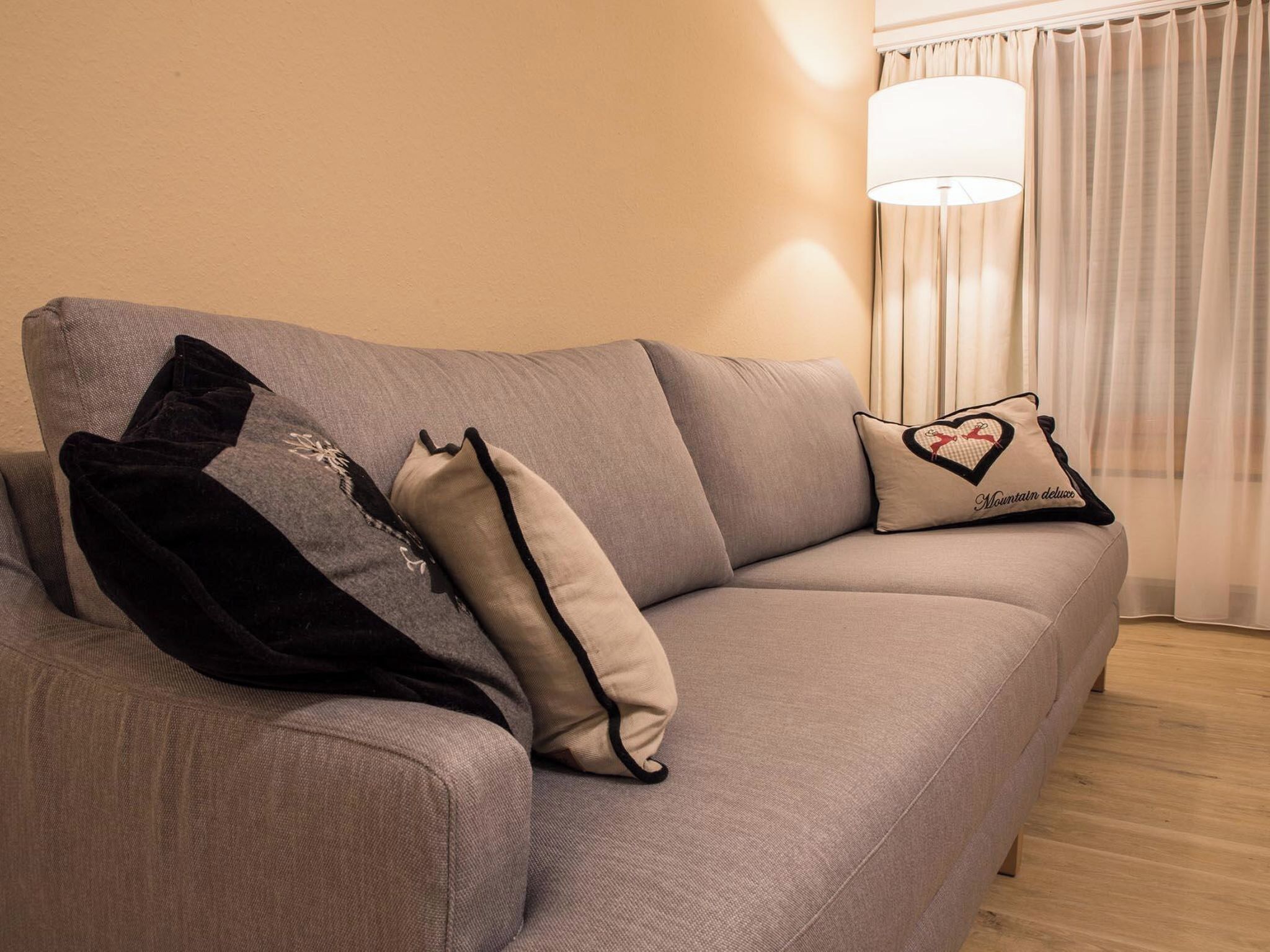 A grey sofa with two pillows, one with a heart design and text, and another with a reindeer design.