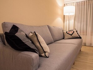 A grey sofa with two pillows, one with a heart design and text, and another with a reindeer design. - I dr Rehwiesa A16 Appartement/Fewo, Bad, WC, 4-Bettwohnung 4-Bettwohnung by Interhome (Arosa)