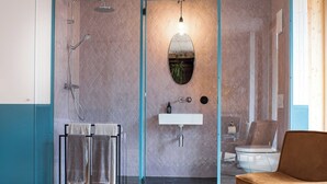 Un baño moderno con cabina de ducha de vidrio, un lavamanos y una silla.