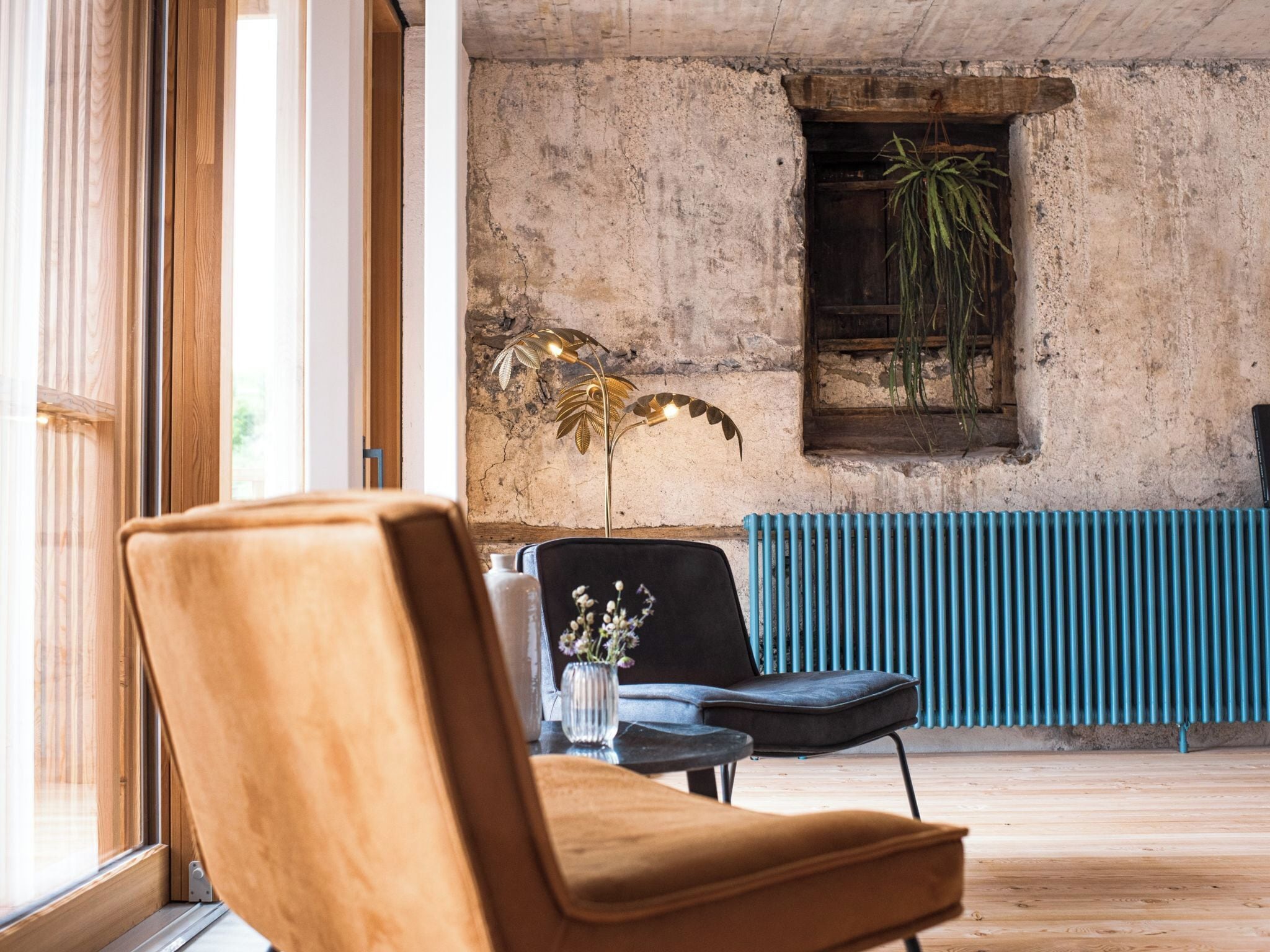 Une pièce avec une grande fenêtre, un radiateur, une plante et une chaise.