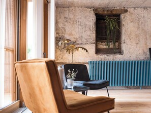 A room with a large window, a radiator, a plant, and a chair.