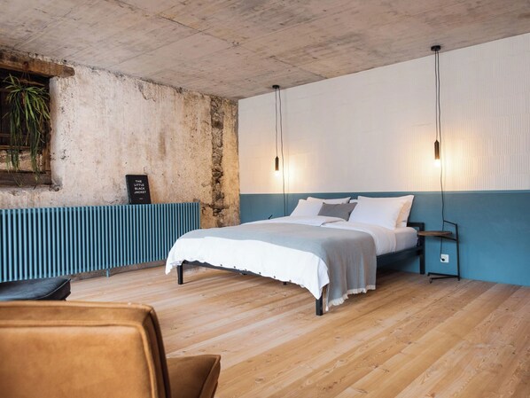 A bedroom with a bed, bedside tables, a radiator, and a hanging plant.