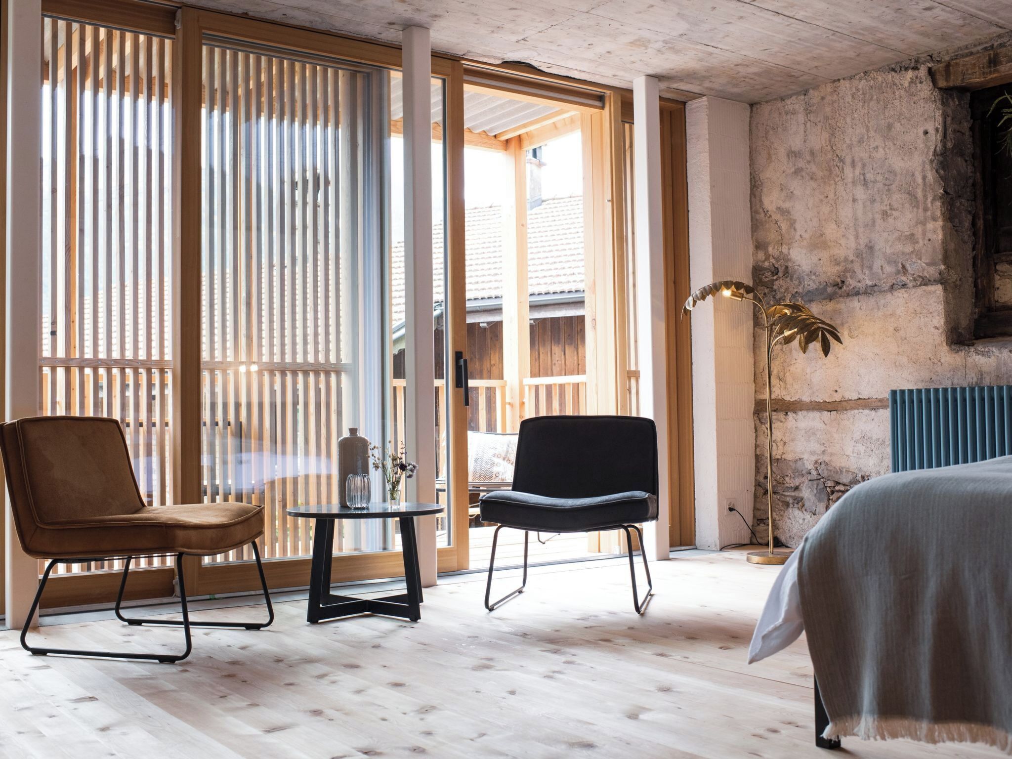 Une pièce comprenant un lit, deux chaises, une table et un lampadaire.