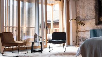 Une pièce comprenant un lit, deux chaises, une table et un lampadaire.