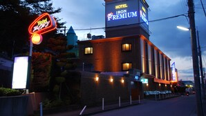 Ett hotell med en iögonfallande neonreklamskylt, en fasad av tegel och en stor, upplyst skylt som visar att det är ett hotell i lyxklass.