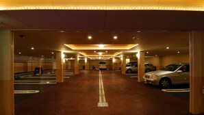 Ett parkeringsgarage med flera våningsplan, markerade parkeringsplatser och en central gångväg.