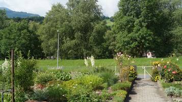 Ein Gartenweg führt zu einem Haus mit umzäuntem Garten und verschiedenen Pflanzen.