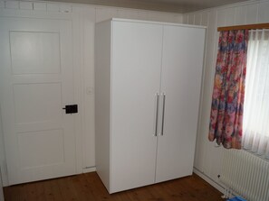 A room with a white wardrobe, a door with a handle, and a window with a floral curtain. - Schils, (Flums). 5 Zimmerhaus mit Bad/Dusche by Interhome (Flums)