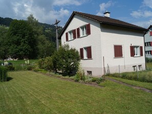 A two-story house with a sloped roof, red shutters, and a fenced yard. - Schils, (Flums). 5 Zimmerhaus mit Bad/Dusche by Interhome (Flums)
