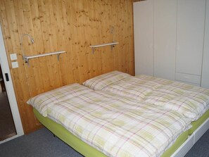 A single-bed room with a wooden headboard, a green mattress, and a white wardrobe. - Schils, (Flums). 5 Zimmerhaus mit Bad/Dusche by Interhome (Flums)