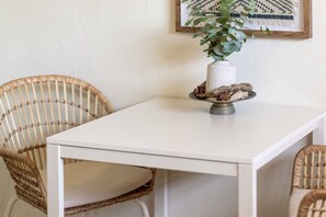 A white table with a vase of green foliage and a decorative plate.