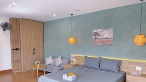 A modern bedroom with a bed, bedside tables, a wardrobe, and a painting on the wall. - Reveur Apartment (Da Nang)