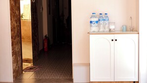 A kitchen area with a white cabinet, a sink, and two water bottles on the counter. - Reveur Apartment (Da Nang)