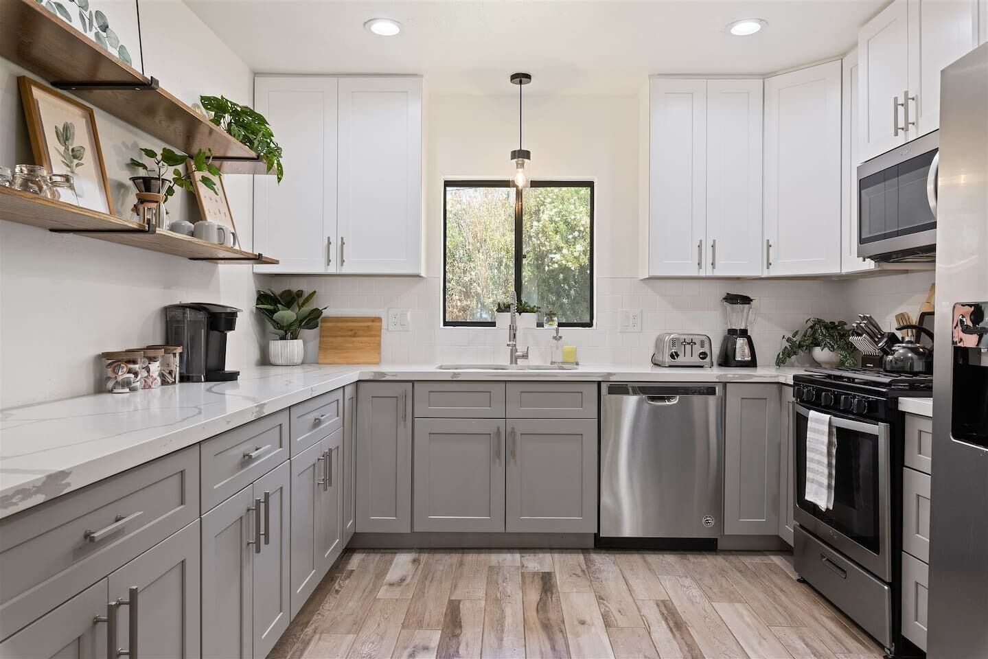 Una cocina moderna con armarios grises, electrodomésticos de acero inoxidable y encimera de madera.