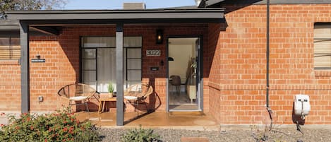 Een modern huis met een bakstenen gevel, een overdekte veranda met twee rieten stoelen en nummer 3022 dat duidelijk zichtbaar is.
